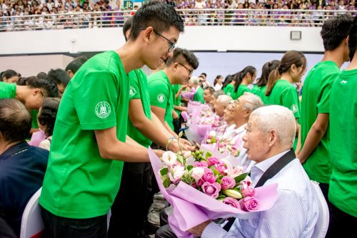 10月2日上午体育馆华中农业大学建校120周年纪念大会，在校学生向老校友献花【学通社记者 彭雨格 摄】